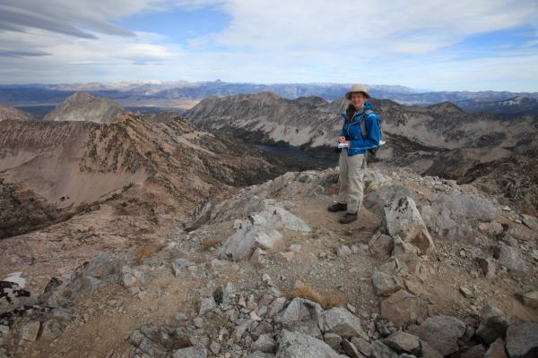 The professor makes an entry in the register of her first third class summit.  Alpine Lake if far below.  Castle Peak is the first conspicuous peak on the horizon left of center.
