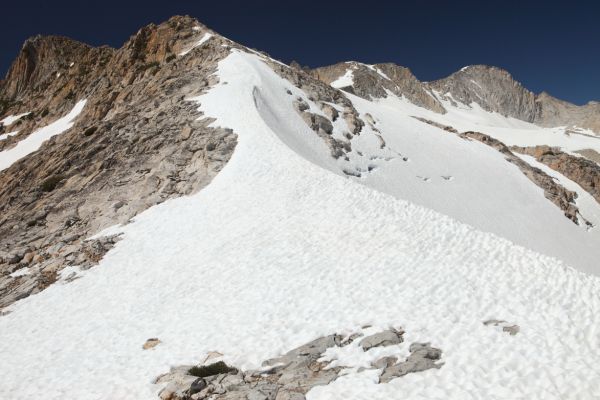 We west head up the east ridge to about the top of the snow on the ridge where it is safe to descend to the north down a "conspicuous curving spur" to the lower The Conness Lake below.  The summit of Mount Conness is on right skyline.
