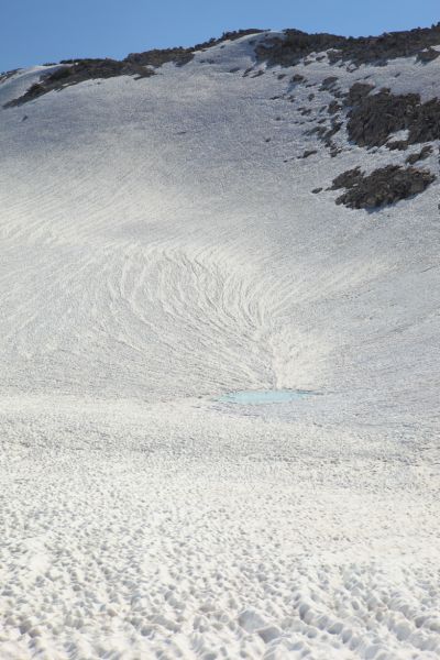 A tarn visible under the rapidly melting snowfield at 11250' southeast of Sky Pilot Col.
