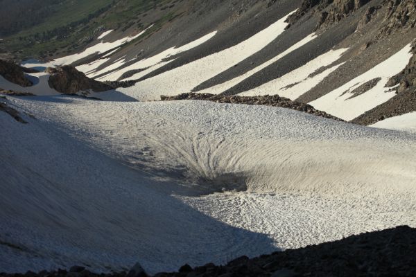 A frozen tarn buried in the snow on the north side of Sky Pilot Col.
