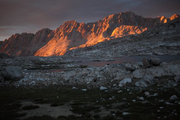 The dark clouds in the background make the direct orange sunlight hitting the peaks even more dramatic.
