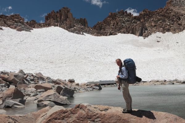 The professor in front of the shallow tarn just north of Lamarck Col, the first notch from the left.  Sun cupped late season snow makes for easy travel to or from the col.
