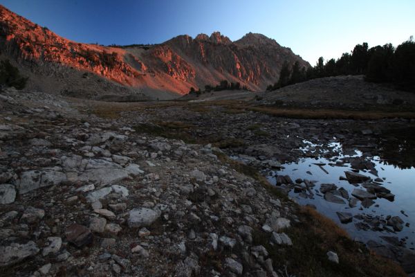 The first rays of morning light stream up the canyon from the east, saturating the peaks surrounding Four Lakes Basin, at just over 9900', in brilliant orange alpenglow.
