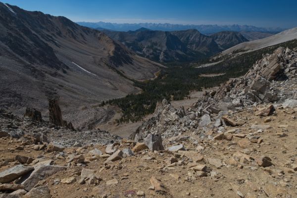 The view west from the low saddle; looking down the drainage west of Hidden and Hummock Lakes.  This drainage empties into Warm Springs Creek, running 90 degrees to it, in front of the dark range of mountains in the upper third of the photo.  Note the dark towers on the ridge (left foreground) leading down into the canyon.
