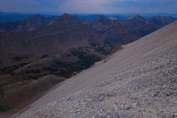 From the D. O. Lee/WCP-9 saddle, the view northwest beyond Bighorn Basin.  Right of center is the entrance to Iron Basin where I came from.  Three quarters to left of frame, close to skyline, is summit of Watson Peak.  Just right of center, vertically in the center, is the horn I climbed behind.  A faint goat trail leads toward the bottom right corner of the frame. 
