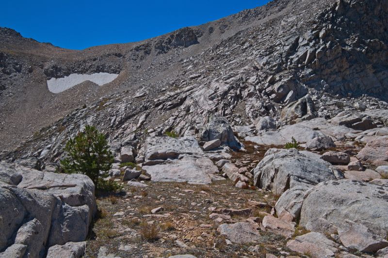 Careful routefinding here saves time and effort.  I find it best to climb just under the vertical rock on the right side of frame, then move left (south) crossing the friction slab as high as practical.  Ascend the most solid terrain as close as possible to that solid outcrop just below the skyline mid-frame.
