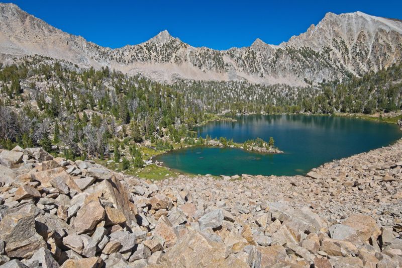 I fished a bit longer than planned, trying unsuccessfully to hook into that elusive 14" trout.  It should take less time to pack up.  It's almost 3 pm.  I camped in those dead trees, left of the closer edge of the lake.  Left my hydration reservoir tucked in by a log last night; some animal bit a hole in it.  Fortunately, my extra 2 liter Platypus bottle will work.
