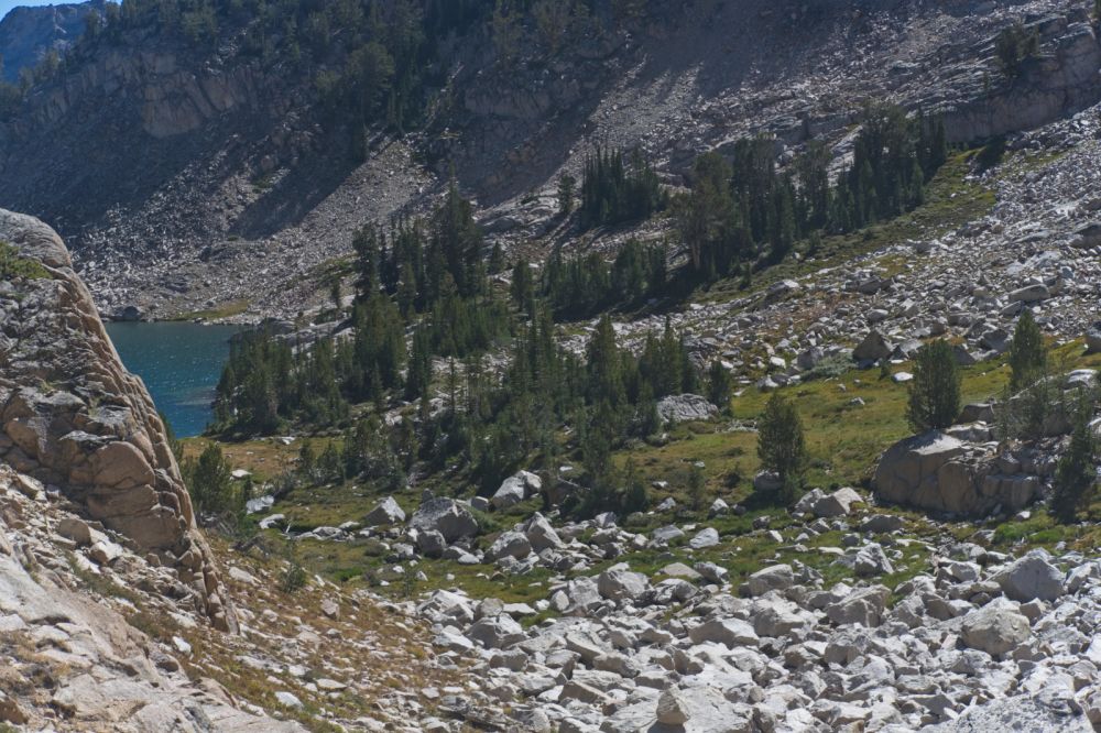 The descent almost to Island Lake, just coming into view on the right (N) side of the drainage.  All the boulder-hopping is easily avoided.  I cross the drainage at the foot of the rockfall in the foreground, and ascend to the ramp toward the higher group of trees on the right (S).
