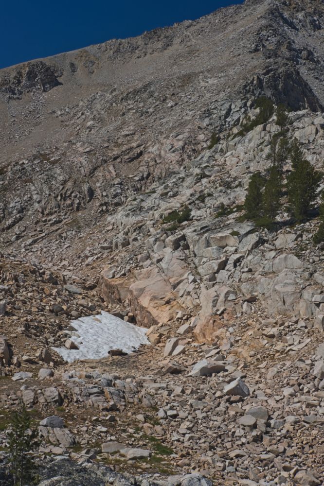 I always ponder the possibilities here.  I want to avoid boulder-hopping, in favor of more stable rock.  I will ascend to the prominent lower group of trees on the right (N), then angle up and left (SW), climbing above the pink solid rock appearing about even with those tree-tops in the photo, and in the center of the frame (horizontal axis).  The pink outcrop is steep, but the angle of the rock is considerably less above it.  I find it best to continue climbing up and left (W) above that, taking advantage of the most solid rock.
