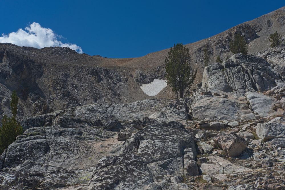 Take advantage of the granite slabs to gain elevation!  The two snow patches are much closer.  The true crossing is under the cumulus cloud, not the low point of the saddle.
